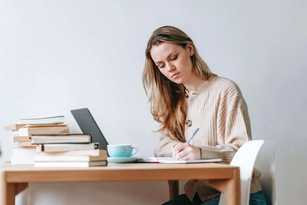 girl writing Optimize Content for SEO with lots off book and cup of tea